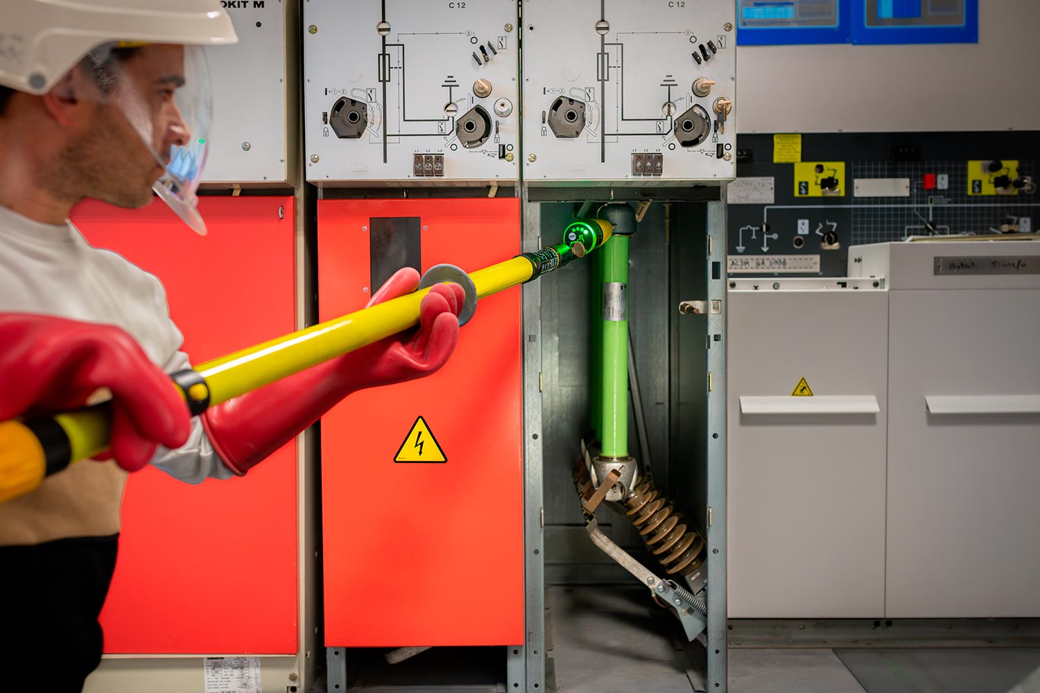 Technicien en formation HTA manipulant un dispositif haute tension avec une perche isolante dans un local électrique sécurisé