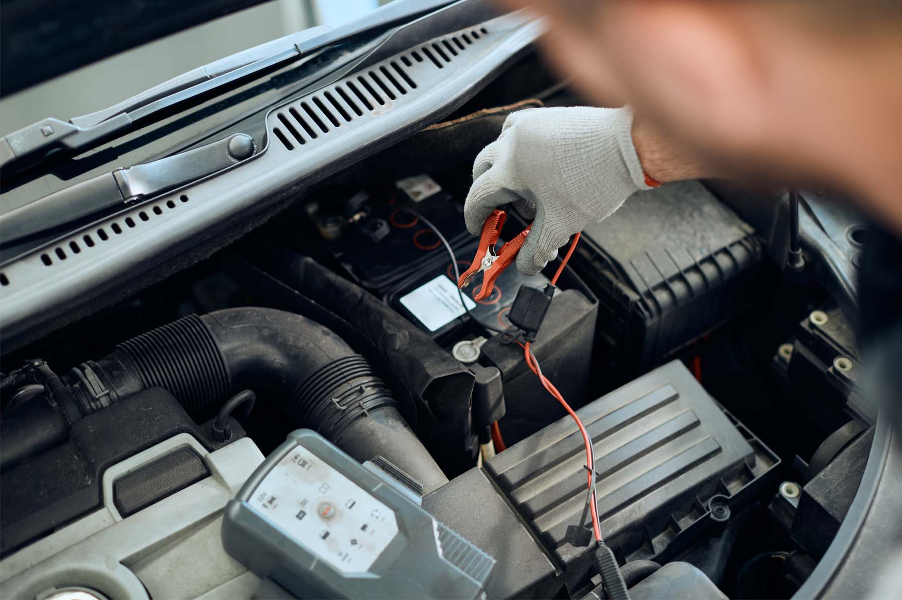 Technicien effectuant une mesure électrique sous tension sur un véhicule à l'aide d'un multimètre, dans le cadre d'une intervention TST IEVE