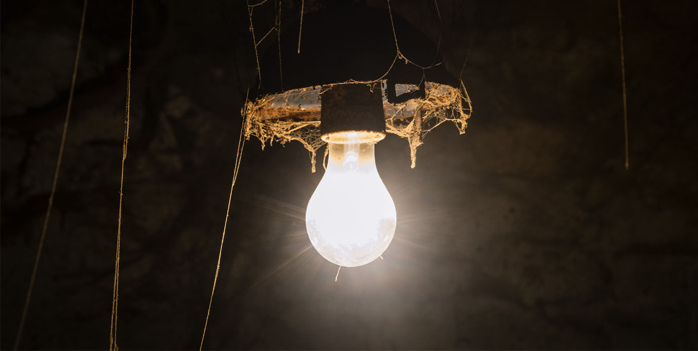 Ampoule éclairant un sous-sol humide, illustrant les risques liés à l’électricité et à l’eau.