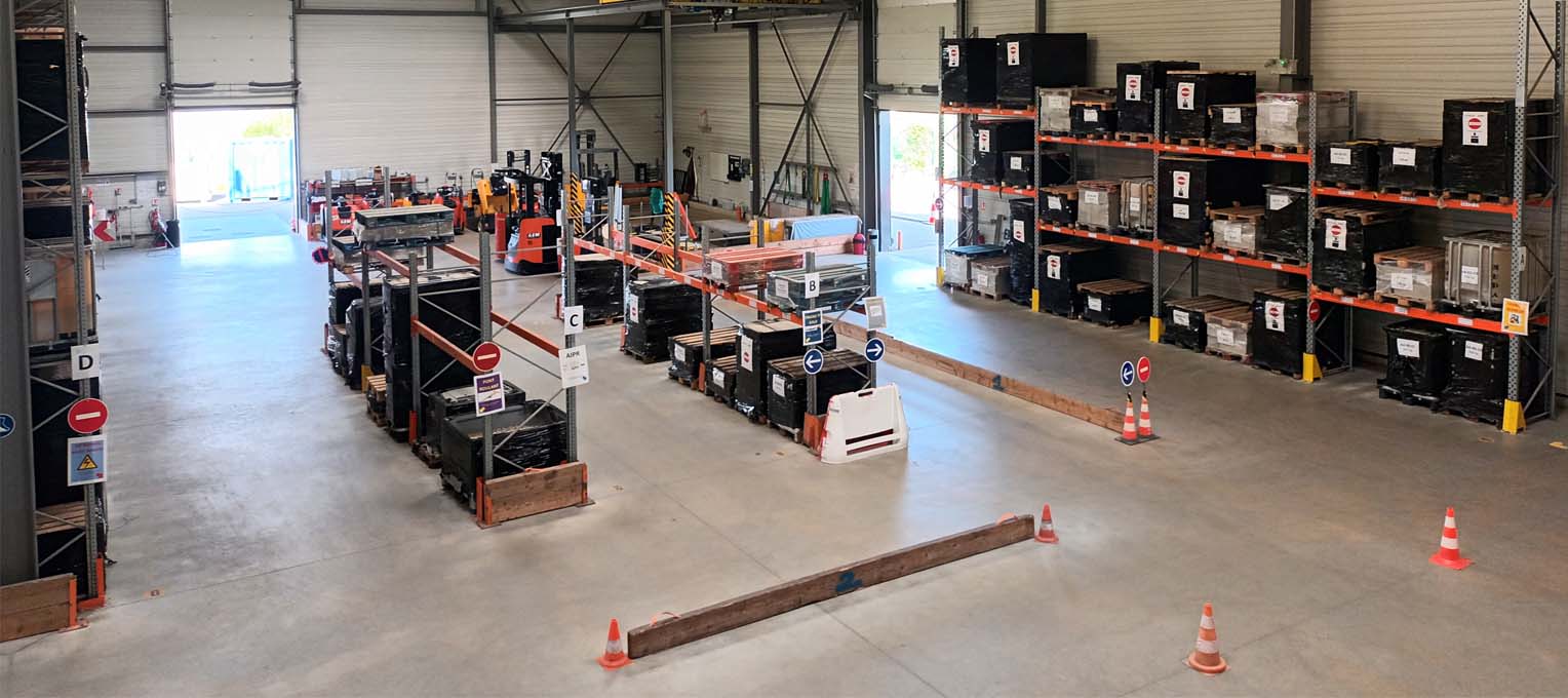 Vue d’ensemble d’un entrepôt industriel avec rayonnages métalliques, racks de stockage et zones de circulation matérialisées pour la gestion des flux logistiques