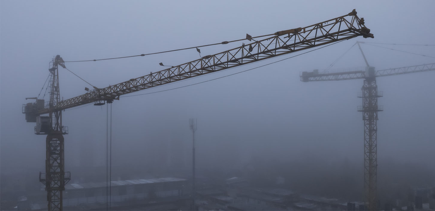 Électricité et eau en milieu, les dangers électriques pour une grue de chantier sous un brouillard.